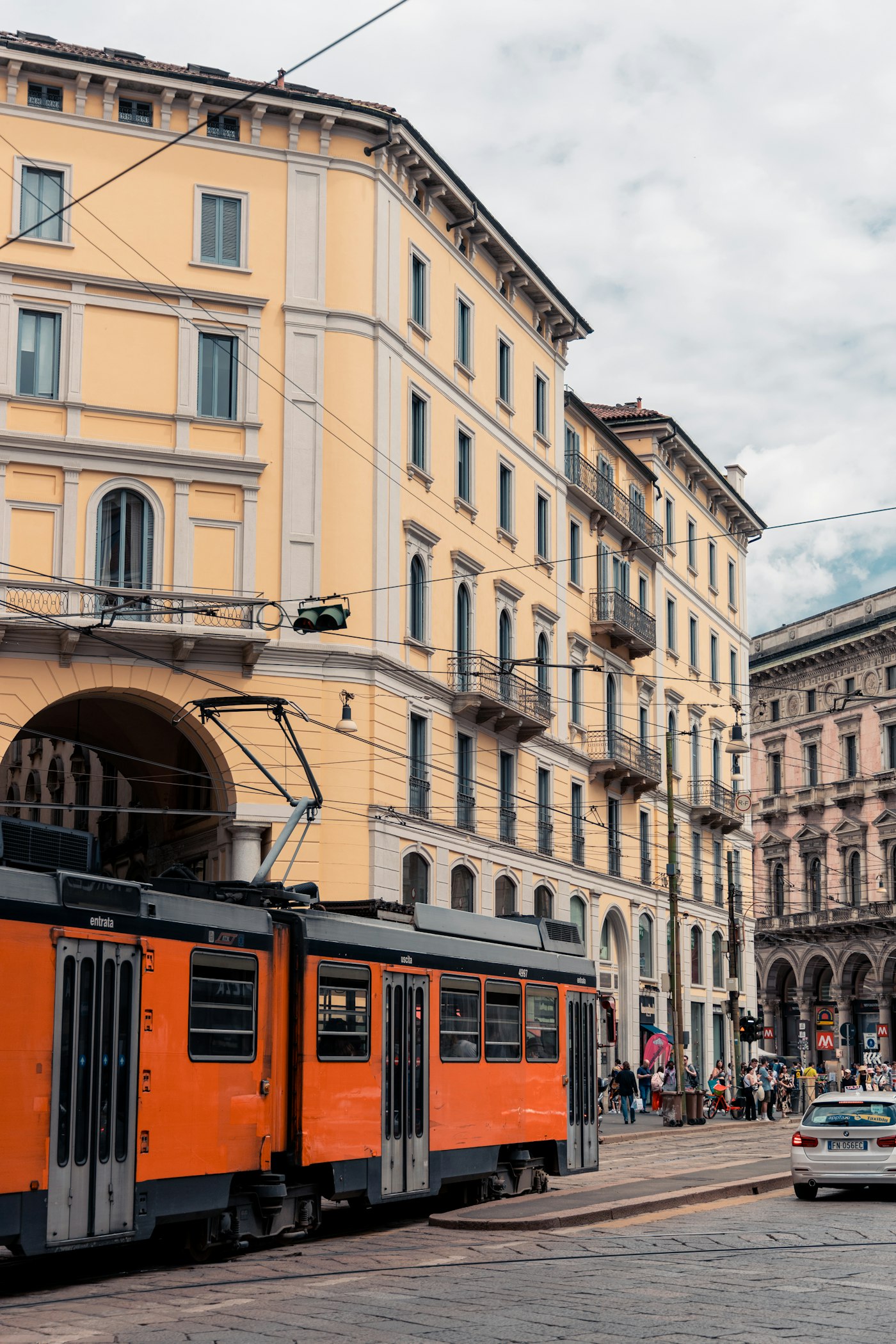 Tram arancione a Milano davanti a un palazzo storico